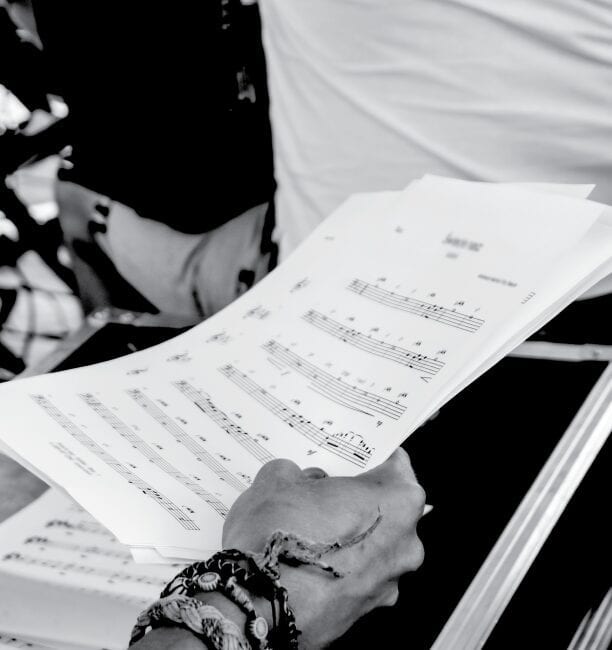 A person holding sheet music in their hands.